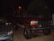 1992 Ford Bronco - 1992 Ford Bronco parked at night, showing its lifted suspension and large off-road tires.