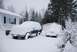 1996 Ford Bronco - Two vehicles are buried in snow during a winter storm, parked in a residential driveway.
