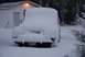 1996 Ford Bronco - A vehicle is completely covered in snow, parked in front of a house during a winter storm.