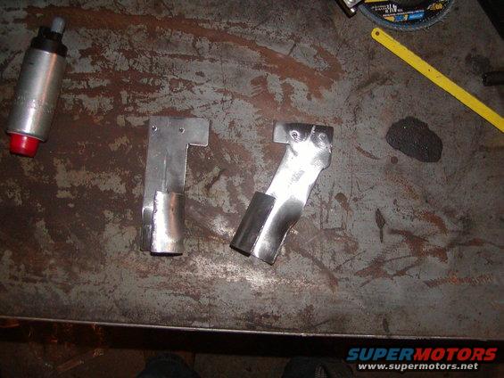 Silver fuel pump with red cap and two metal brackets on a workbench