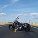 2000 Harley-Davidson Softail - A black motorcycle sits on an asphalt road under a cloudy blue sky.