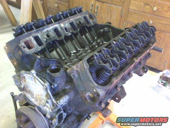 Engine block with valve covers removed, showing pistons and valve train