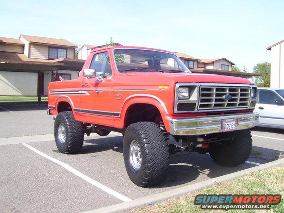 Red 1986 Ford Bronco with lifted suspension and large tires
