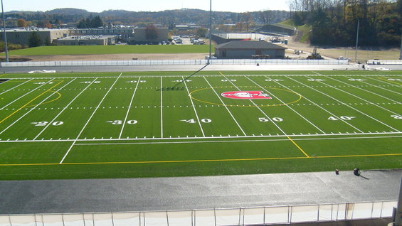 Football field with yard lines and a red logo in the center circle