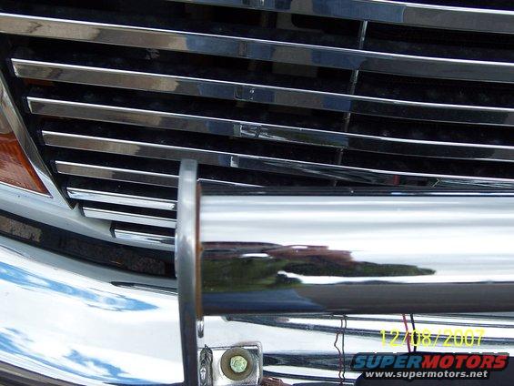 Chrome grille with horizontal bars and a chrome bumper guard on a white vehicle
