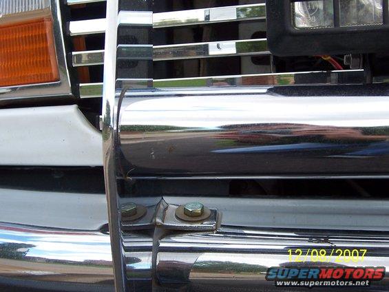Chrome grille guard with visible bolts on a white vehicle's front end