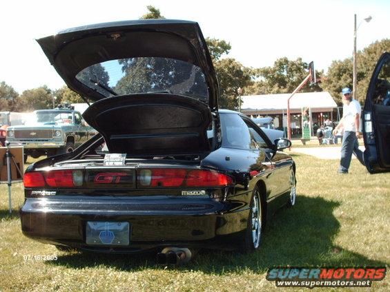 Black Mazda Probe GT with trunk and driver door open, parked on grass