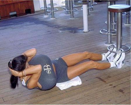 Woman doing situps with feet braced by bar stools