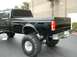 1997 Ford F-350 - This black pickup truck features a lifted suspension and oversized off-road tires.