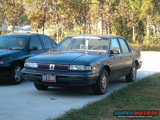 1996 Oldsmobile Ciera sedan, 3q-front view, dark blue. License plate reads 'GIT-R-DONE'