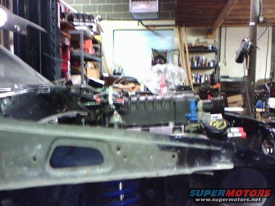 Engine bay with blue springs visible below, in a workshop setting