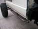 1986 Toyota Hilux - Custom metal rock sliders are attached to the side of a white vehicle with a large off-road tire visible.