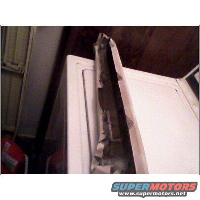 Torn weather stripping on a white appliance, possibly a washing machine or dryer