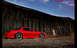 1901 Honda Odyssey - A red sports car sits in front of an old, rustic barn under a blue sky.