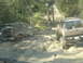1989 Ford Bronco - Off-road vehicles struggling through a muddy terrain on a wooded trail.