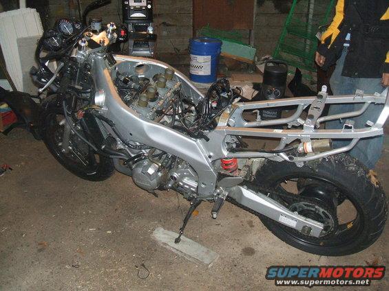 Motorcycle frame, engine, front wheel, and rear wheel disassembled in a garage