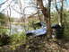 1989 Ford Bronco - This vehicle appears to be stuck in a wooded area, leaning against trees with a lake in the background.