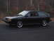 1987 Volkswagen Scirocco - A black 1987 Volkswagen Scirocco is parked on a road with a wooded area behind it.