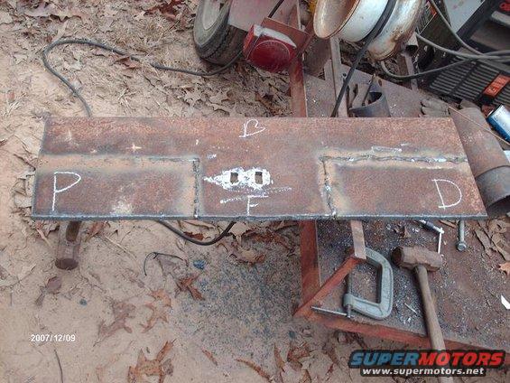 Welded steel plate with chalk marks P, B, F, and D. Tools and trailer parts in background