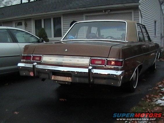 Brown sedan with chrome bumper and taillights, parked next to a silver car