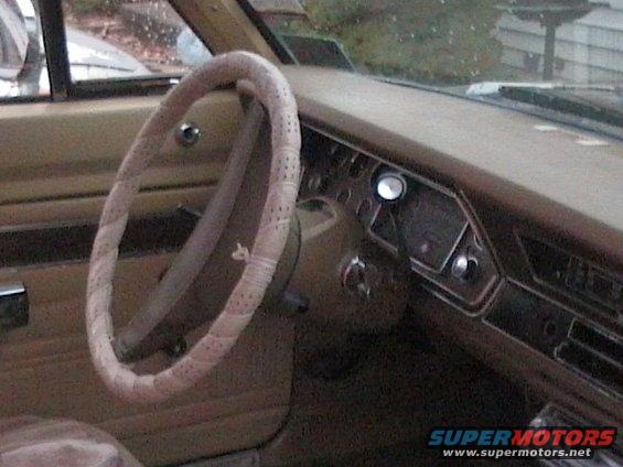 Interior shot of a car's dashboard and steering wheel with a patterned cover