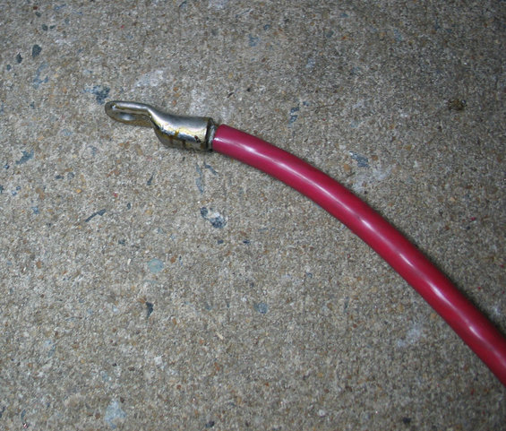 Red battery cable with metal ring terminal on concrete