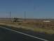 1995 Ford C-350 (Centurion Conversions) - A dinosaur statue stands beside a highway, a common roadside attraction in open country.