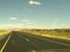 1995 Ford C-350 (Centurion Conversions) - Driving on a highway through a vast desert landscape under a partly cloudy sky.