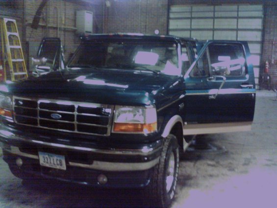 Dark green Ford truck with tan trim, driver's door open. License plate reads 337LCB