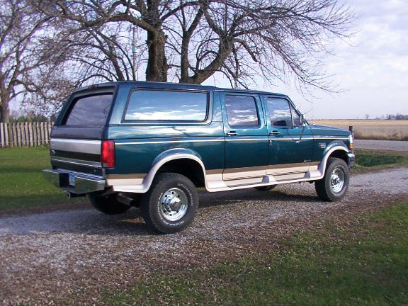 1995 Ford C-350 (Centurion Conversions) extended cab pickup with camper shell, parked on gravel drive