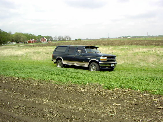 Dark blue 1995 Ford C-350 Centurion Conversions SUV parked in a grassy field