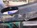 1995 Ford C-350 (Centurion Conversions) - Close-up of a black plastic automotive part, likely a front valance, showing a circular opening and some damage.