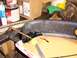 1995 Ford C-350 (Centurion Conversions) - A close-up view of a damaged automotive part being repaired with adhesive and a clamp.