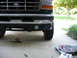 1995 Ford C-350 (Centurion Conversions) - Front view of a Ford truck, showing the grille, bumper, and a fog light, with tools laid out on the concrete.