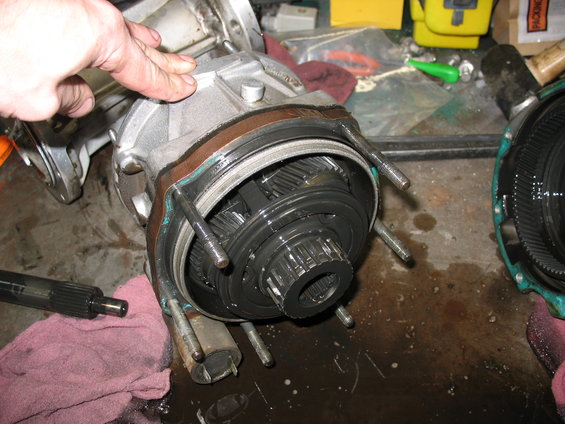Transmission gears and housing disassembled on a workbench with a hand pointing to the seal