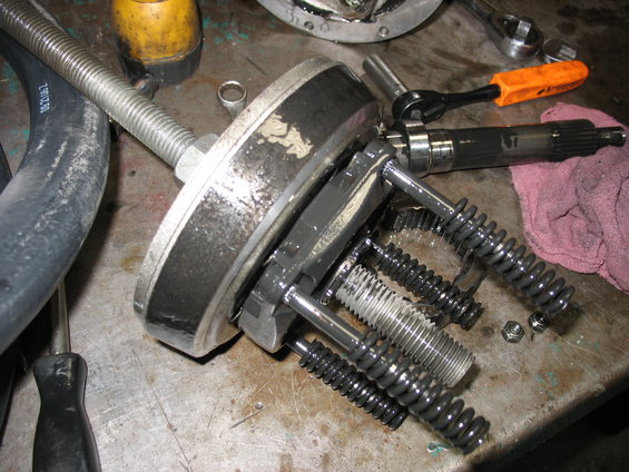 Close-up of a disassembled automotive component with springs, bolts, and gears on a workbench
