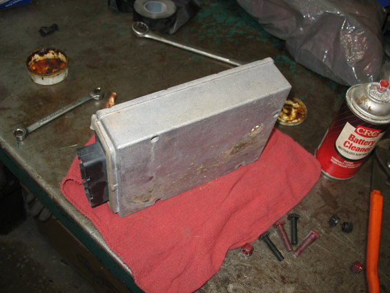 Engine control module on a red cloth with tools and a can of battery cleaner
