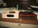 1995 Ford C-350 (Centurion Conversions) - Two wooden overhead console parts with dark inserts sit next to a dark brown plastic console part on a desk.