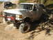1989 Ford Bronco - A muddy 1989 Ford Bronco tackles a rocky off-road course, with a second vehicle visible in the background.