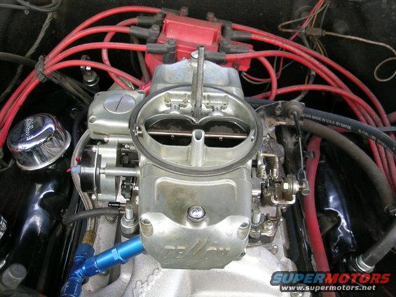 Engine carburetor with red spark plug wires and a chrome cap