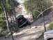 1989 Ford Bronco - A black off-road vehicle is shown struggling on a steep, muddy incline surrounded by trees.