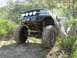1989 Ford Bronco - This heavily modified truck, likely from the late 1980s, navigates a challenging off-road trail.