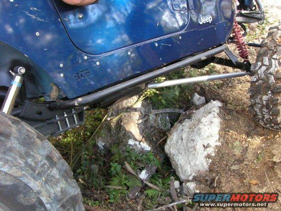 Blue Jeep Wrangler side panel with "Jeep" text, off-roading over rocks