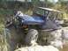 1989 Ford Bronco - Two people attempt to free a blue Jeep Wrangler that is stuck on a rocky incline during an off-road excursion.