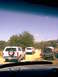 1989 Ford Bronco - Several SUVs are parked on a dirt road under a clear blue sky.