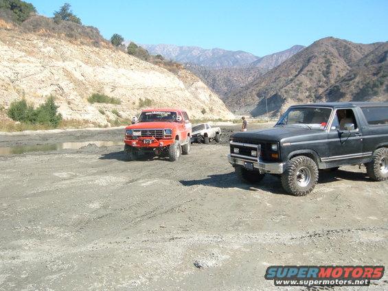 Black Ford Bronco with off-road tires, front 3/4 view, in a dry, mountainous landscape