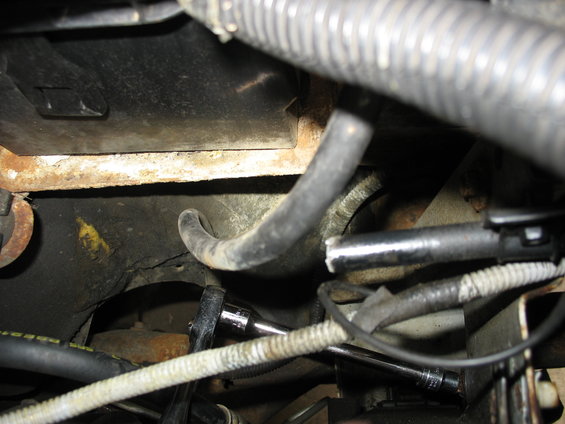 Close-up of engine bay showing hoses, wiring, and a socket wrench on a bolt