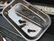 1995 Ford C-350 (Centurion Conversions) - A metal tray holds four rusty bolts and a socket extension, resting on a vehicle's engine bay components.