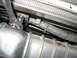 1995 Ford C-350 (Centurion Conversions) - Mechanic using a socket wrench on a bolt in the engine bay, focusing on a section of wiring.