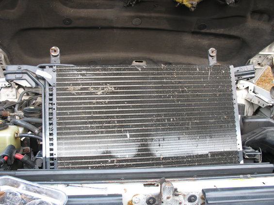 AC condenser in engine bay, covered in debris